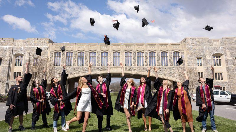 A group of Hokies tossing graduation caps in the air